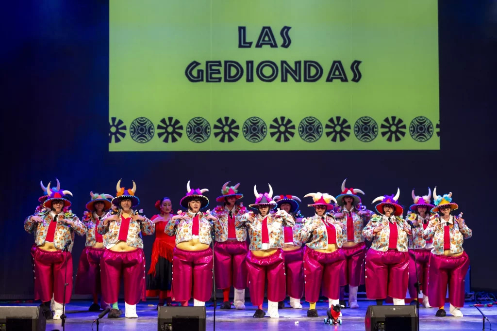 Groupe de Murga se produisant au Carnaval de Tenerife 2026 avec des sifflets kazoo et des costumes satiriques au Recinto Ferial.