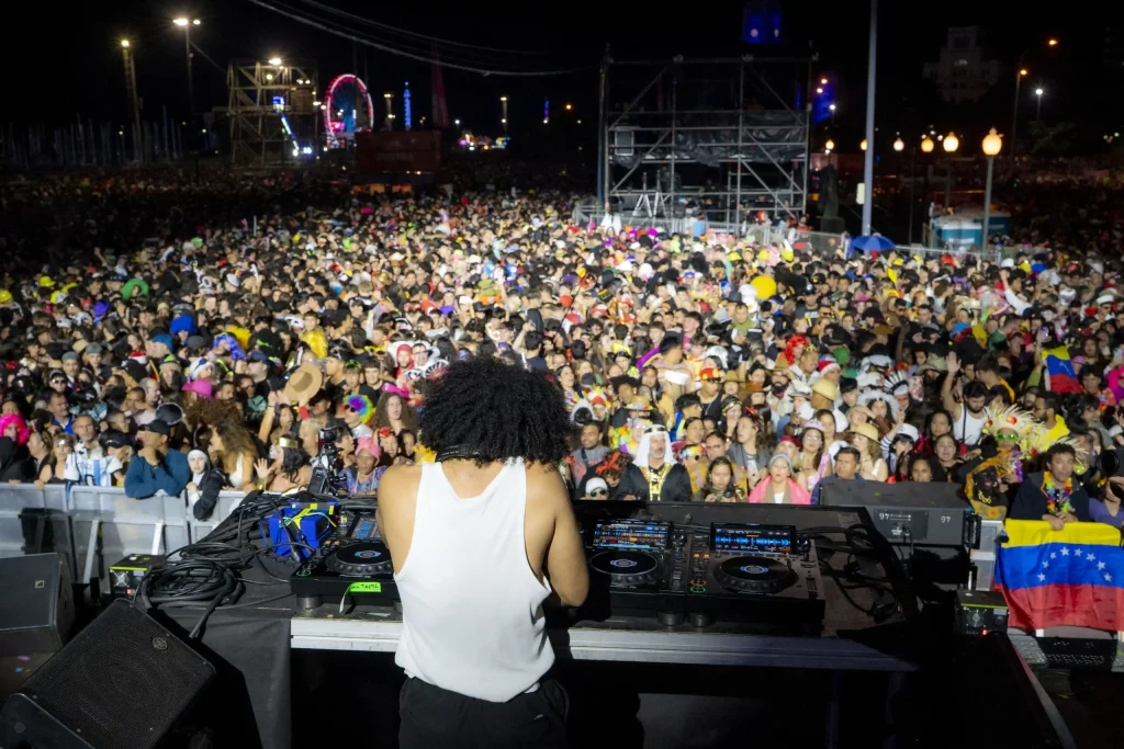 Fête nocturne animée du Carnaval de Tenerife à la Plaza de España avec des lumières de scène, des costumes colorés et des milliers de personnes.