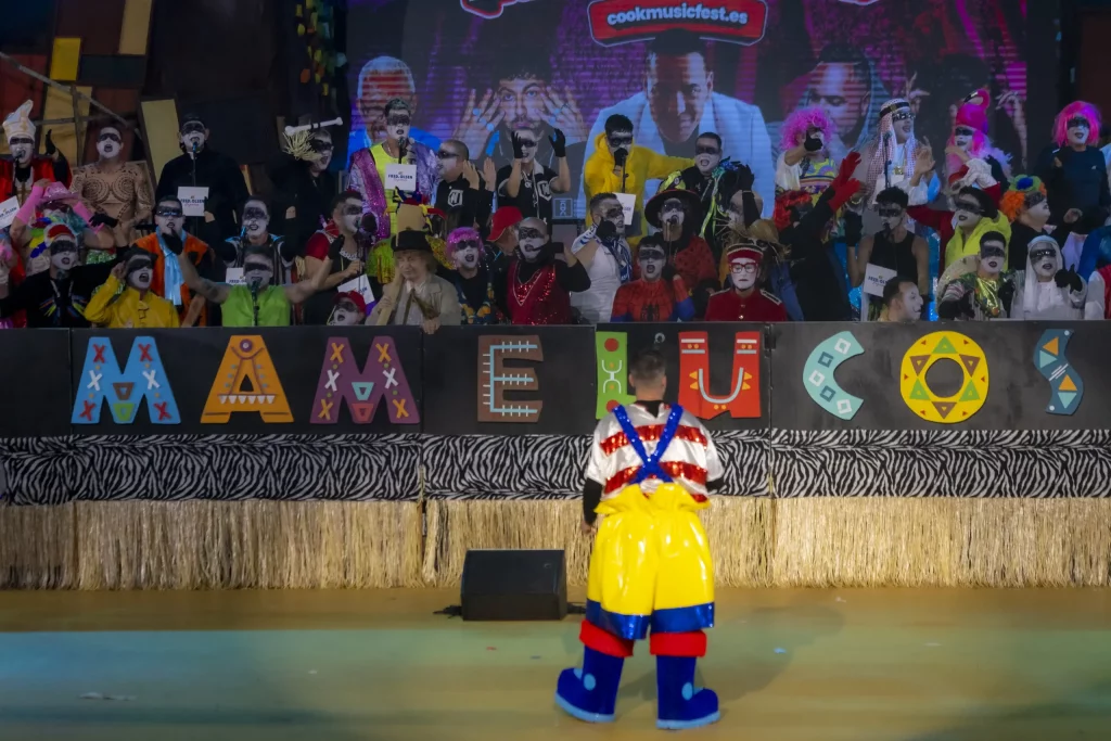 Groupe de Murga se produisant au Carnaval de Tenerife 2026 avec des sifflets kazoo et des costumes satiriques au Recinto Ferial.