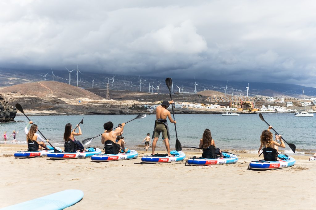 Instructor de paddleboard enseñando técnica SUP a principiantes en Costa Adeje Tenerife experiencias